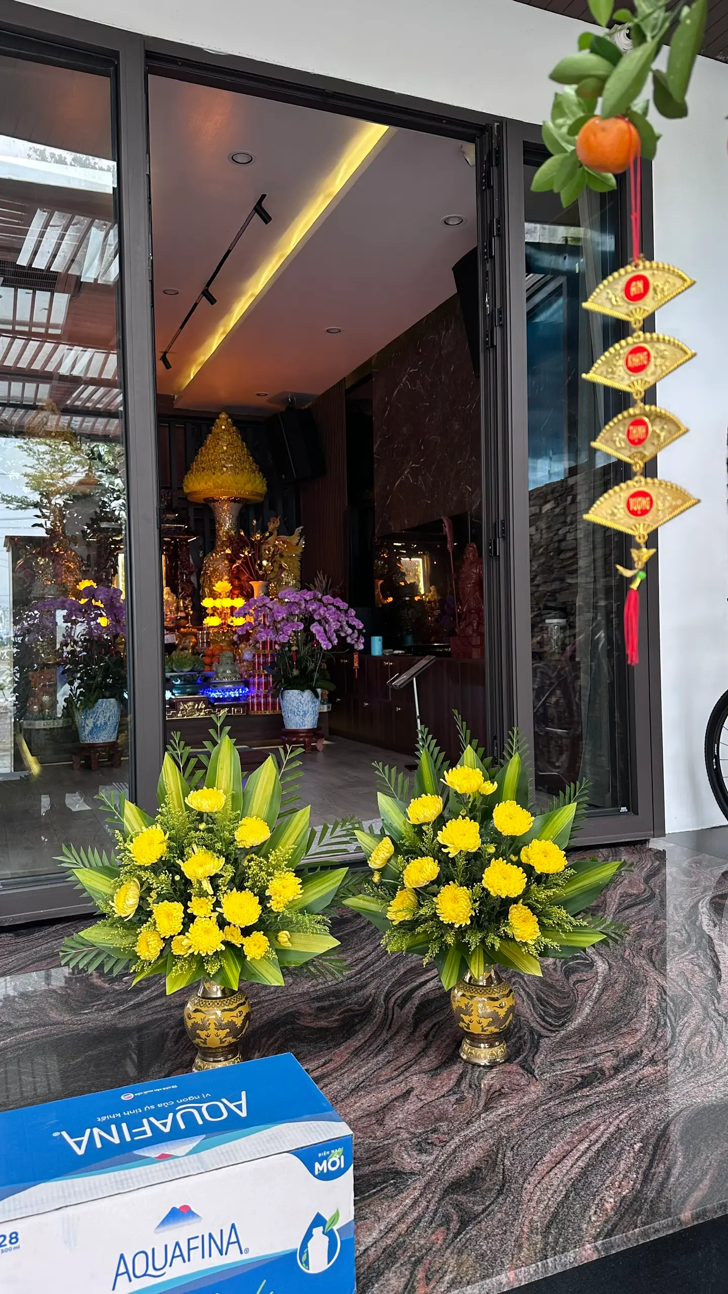 Cặp bình hoa cúc vàng cắm bình đồng đặt trên bàn đá