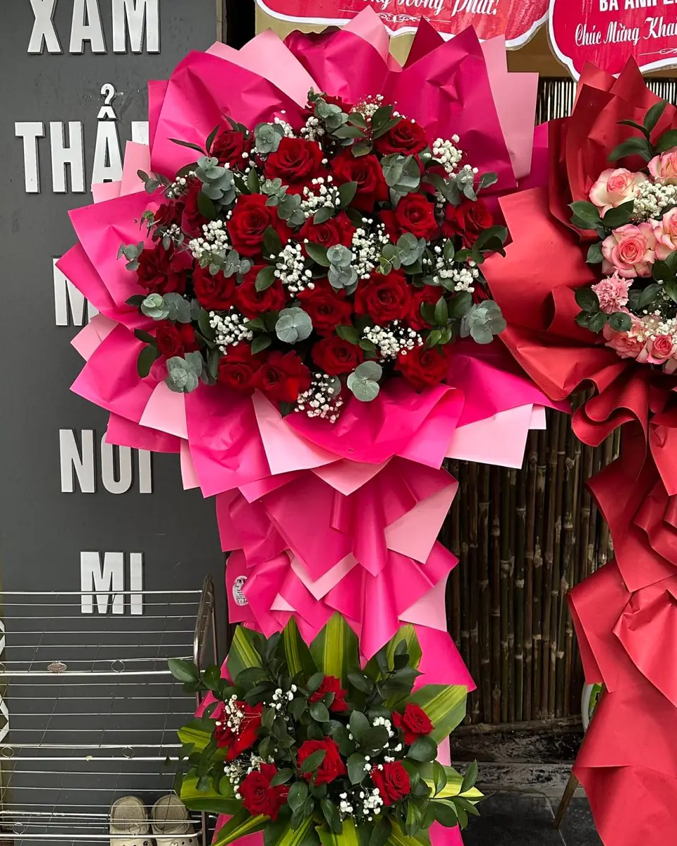 Kệ hoa khai trương hai tầng, hoa hồng đỏ nhung và baby trắng trên giấy gói hồng sen