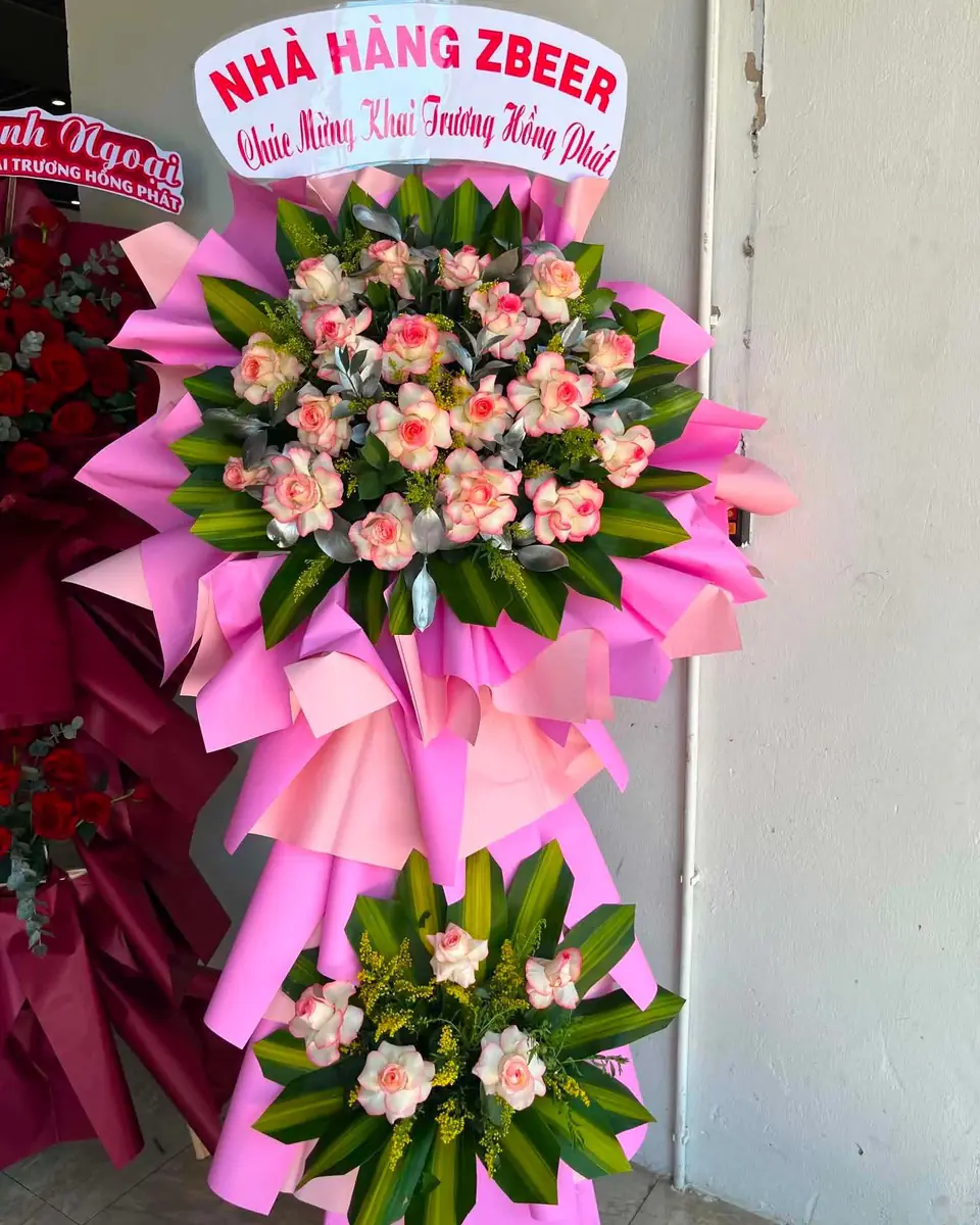 Kệ hoa khai trương hai tầng tông hồng pastel, hoa hồng kem viền hồng xen lá xanh